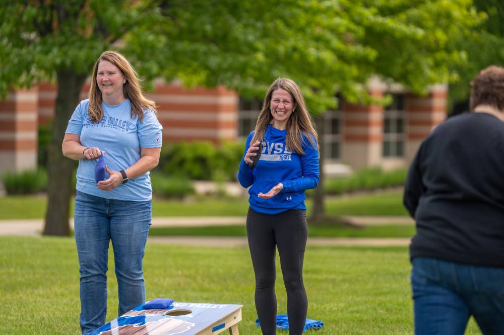 Two players smile and laugh holding bags